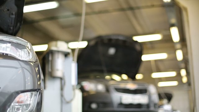 Bumper with foglamp of car standing on hoist at workshop
