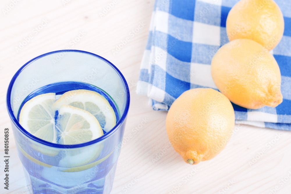 Wall mural water with lemon and mint in blue glass on the table top view