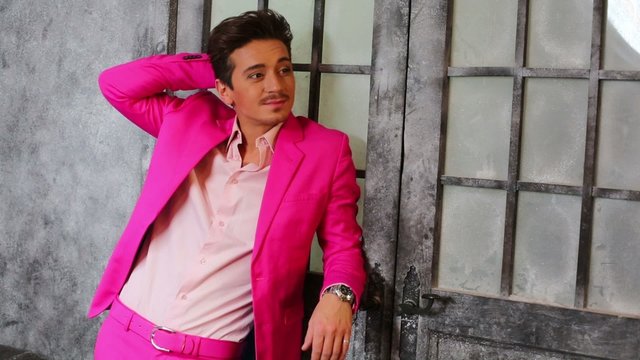 Young man in pink suit against old icy door at studio