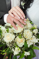 Obraz na płótnie Canvas couple's hands with rings on wedding bouquet.