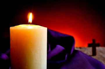 lit candle and a Christian cross