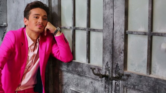 Young man in a bored pose with pink suit against closed old door