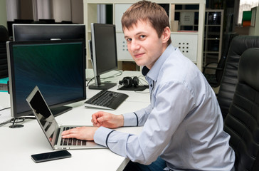 Fototapeta premium Young handsome happy man with computer in the office.