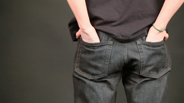 Boy stand in jeans at puts hand to pockets