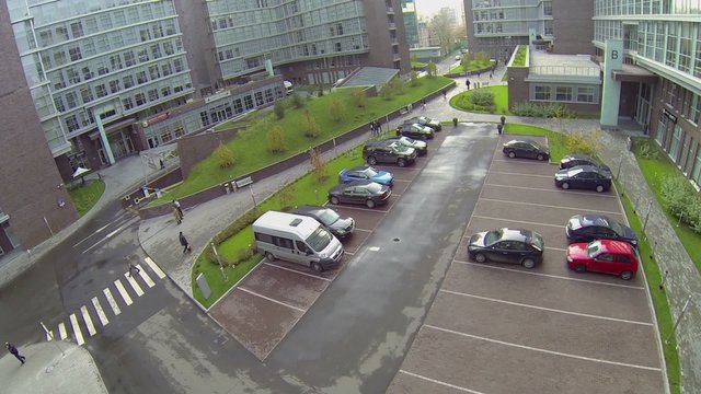 People walk near parking of offices and hotel complex