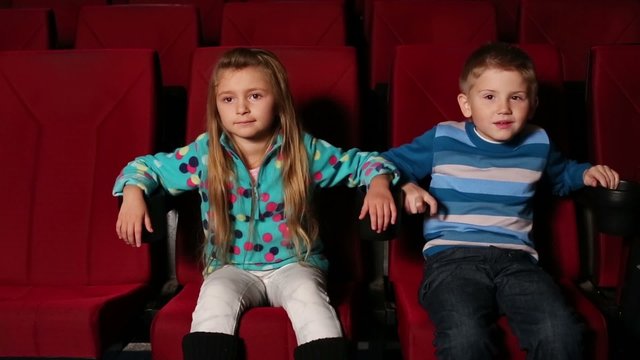boy and girl watching a movie in cinema, beside them sits boy