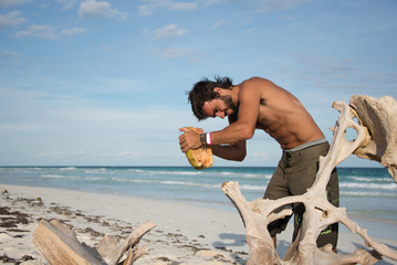 Strong Latin Male Survivor Opening a Coconut.