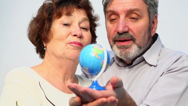 Senior couple hold earth miniature and speak, closeup
