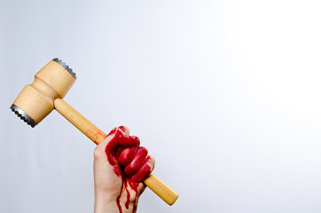 Bloody hand holding kitchen mallet