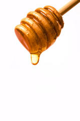 Honey dripping from a wooden honey dipper isolated on white - 80164889