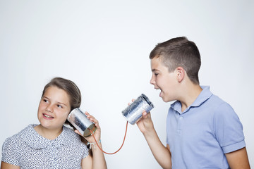 Kids using a can as telephone against gray background
