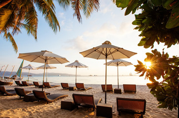 Sun umbrellas and beach chairs on tropical beach