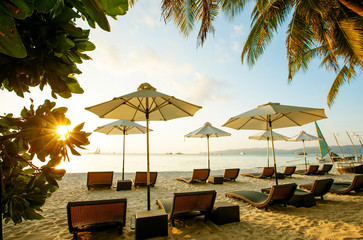 Sun umbrellas and beach chairs on tropical beach