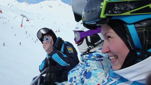 One of three skiers makes photo by cellphone during ropeway ride