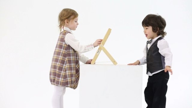 Little happy girl and boy play with abacus on big white cube