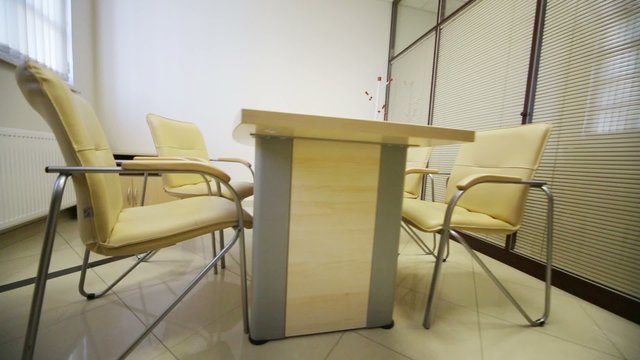 table and chairs in meeting hall with louvers on glass wall