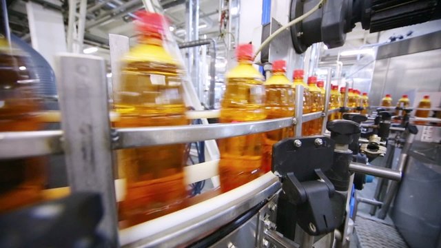 Bottles of fresh light beer with red caps moving on conveyor