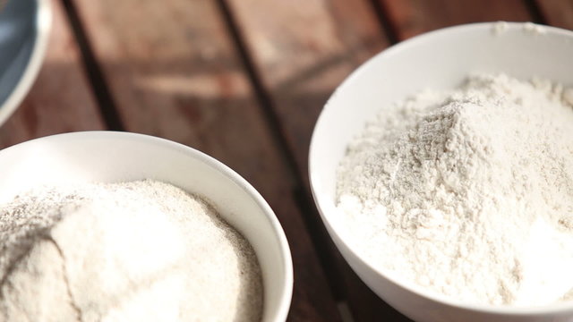 closeup transfer from wheat to rye flour on wooden table	