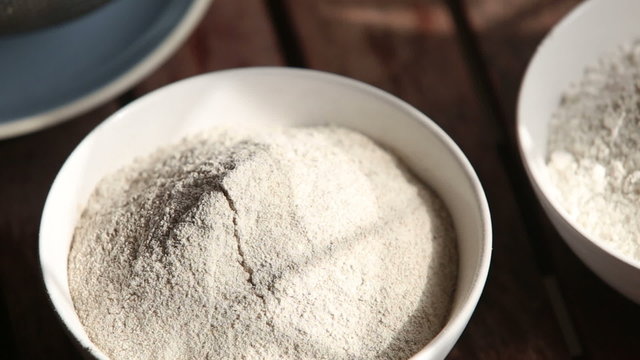 closeup transfer from wheat to rye flour on wooden table	