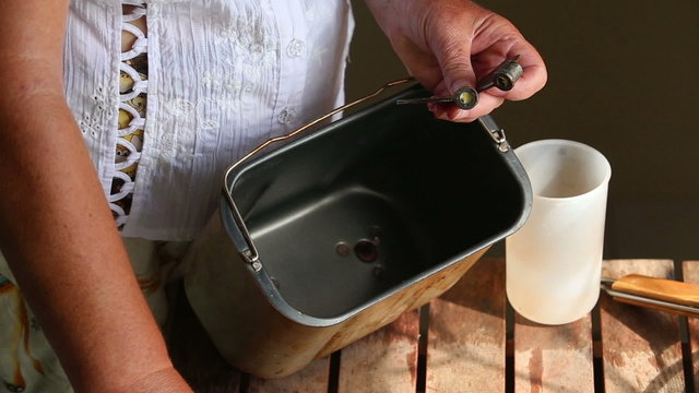 caucasian woman hands oils bottom of container of baking machine