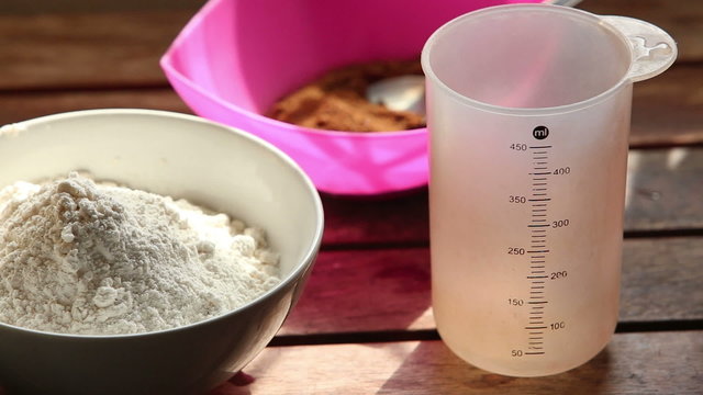 caucasian woman pours water into measuring cup on table near bow