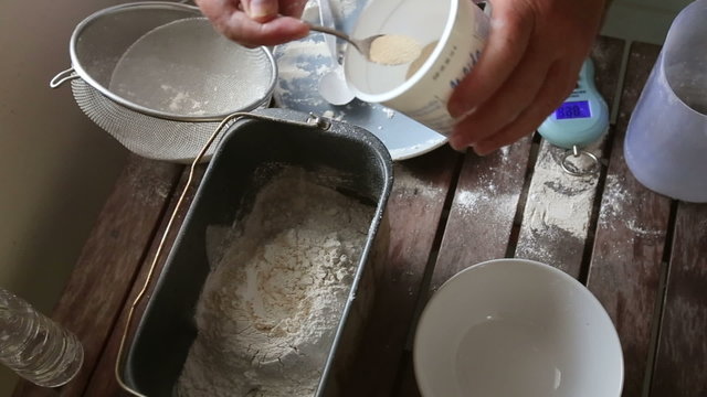 caucasian woman hands put yeast into flour in bakery machine	