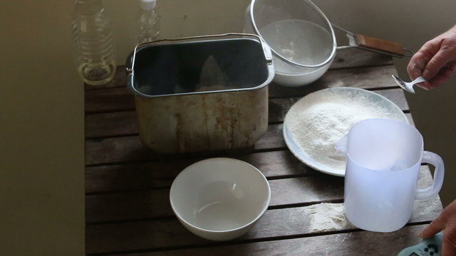 caucasian woman puts flour into container for bread making	