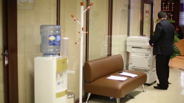 Man in black suit copies documents in modern office