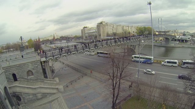 People walk by Patriarshy bridge against cityscape 