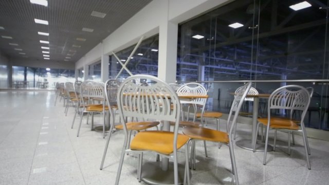 Rows of tables with chairs near window in exhibition center