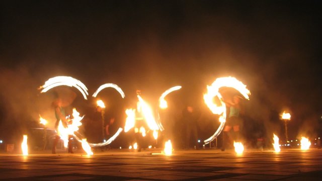 Group of man and women performing a show with flames, timelapse