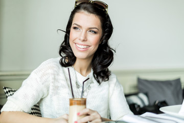 Gorgeous lady smiling in a restaurant while holding her coffee