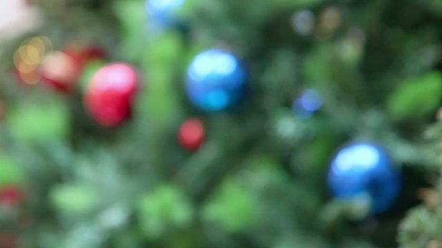 Cone and toy balls on branch of artificial fir-tree at shop