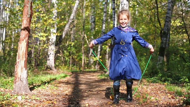 Little girl with blue jacket jumping rope in the forest