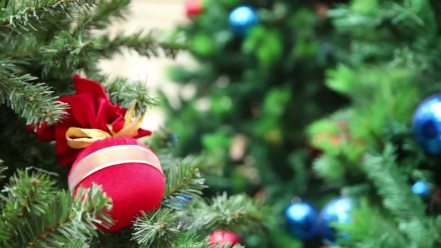 Red miniature balls, bags, toys on branch of artificial fir-tree