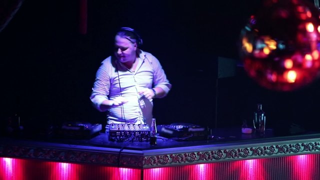 DJ mixes music tracks with cd-player and mixer in nightclub 