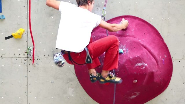 Boy climbs by rock wall during rock-climbing competition