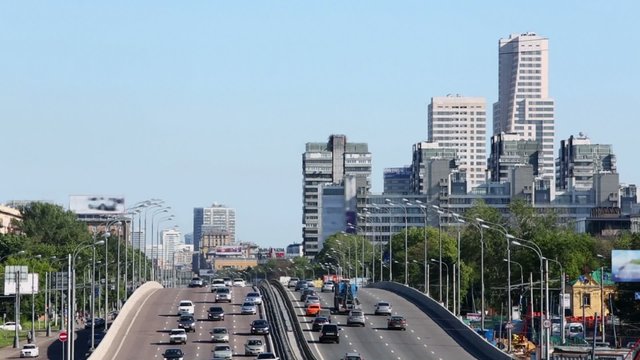 Many cars ride by road and bridge in large city
