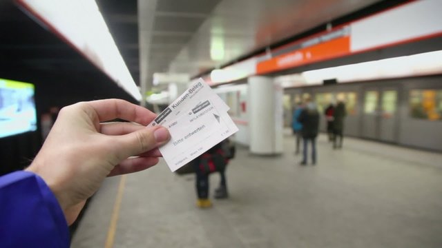 Hand hold two tickets at metro station with passengers and train