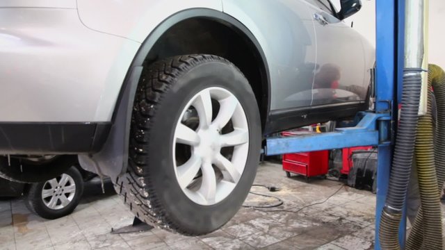 Man lifts offroader by elevator in car service center, closeup