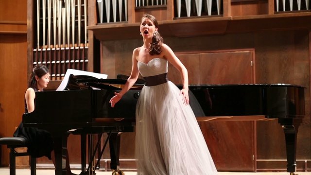 Woman pianist plays the piano and singer sing opera song