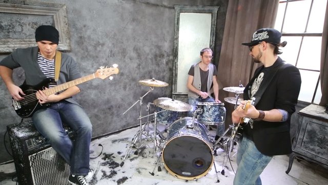 Two guitarists and drummer play in room powdered with snow