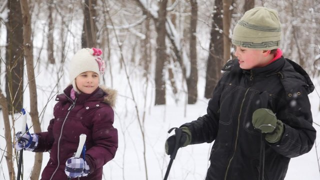 Two kids with ski poles staying and talking near forrest
