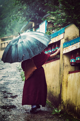 Buddhist monk with umbrella spinning prayer wheels