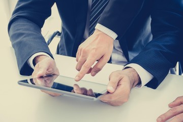 Businessmen using tablet computer with one hand touching screen