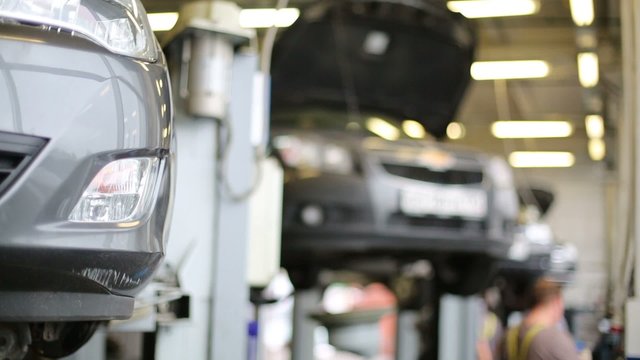 Bumper with foglamp of car standing on lift at workshop