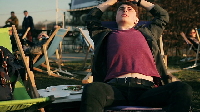 Student lying on sunbed and relaxing in outdoor bar