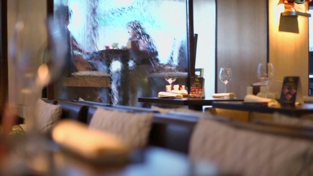 Several clients sit behind water walls in resturant, panoramic motion