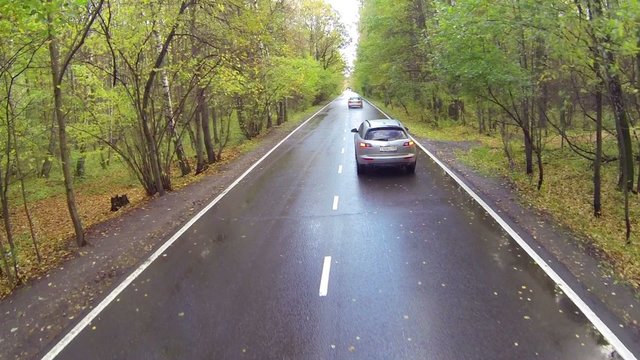 Silvery car moving slowly getting passed by another in forest