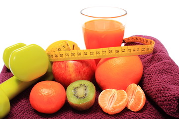 Fresh fruits with tape measure, glass of juice and dumbbells
